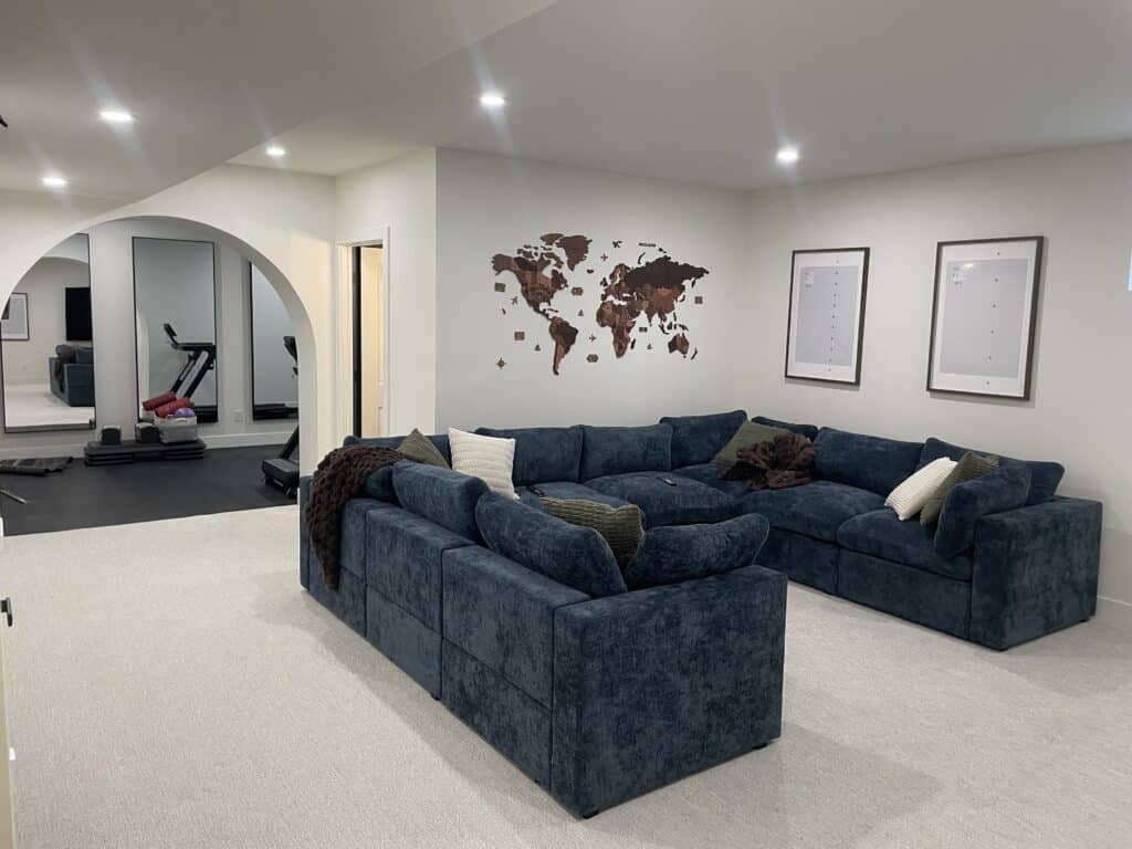 Finished Calgary basement development with blue sectional family room and adjoining home gym