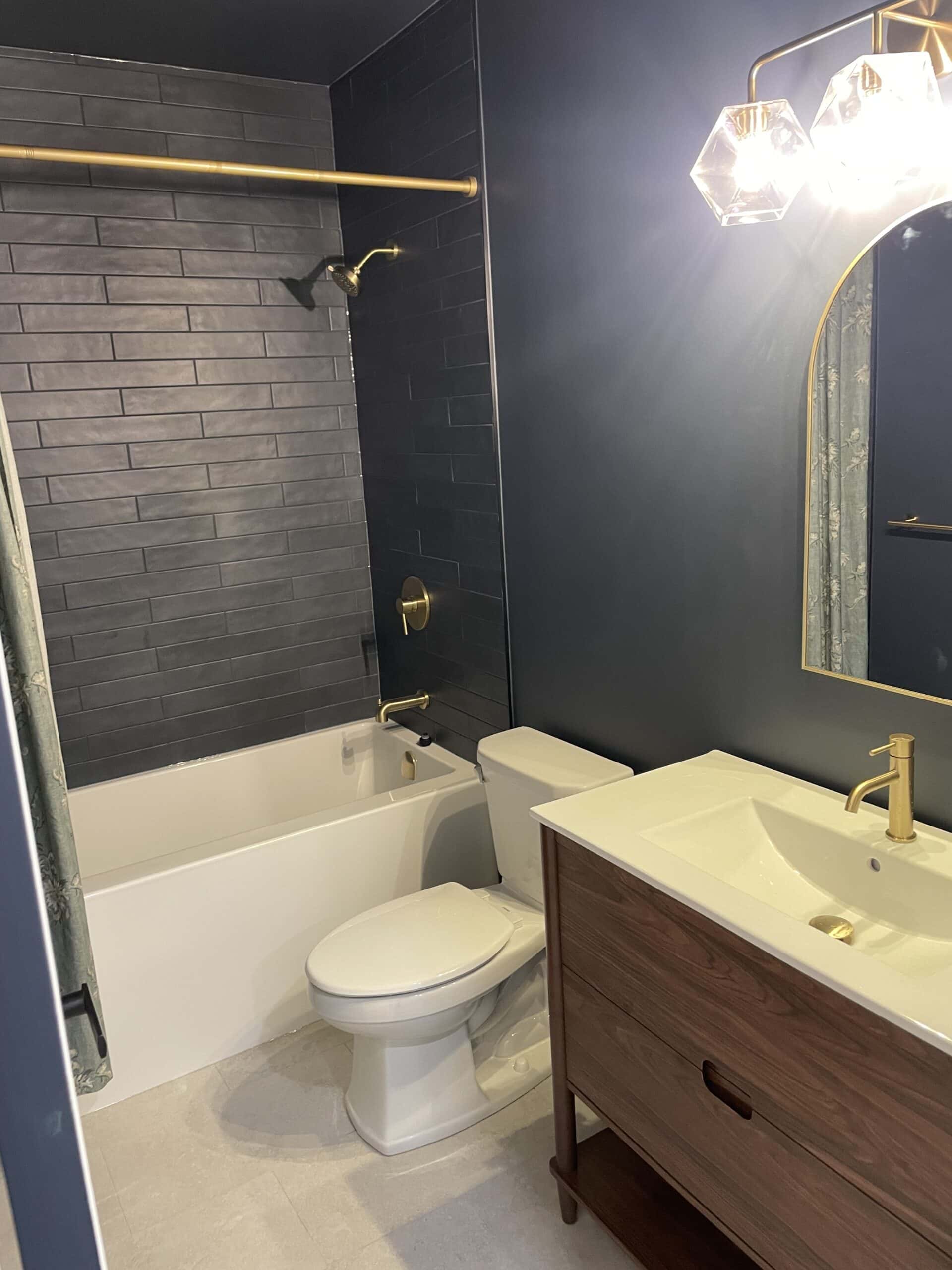 Finished custom bathroom in Garrison Green Calgary basement development with dark tile and brass fixtures