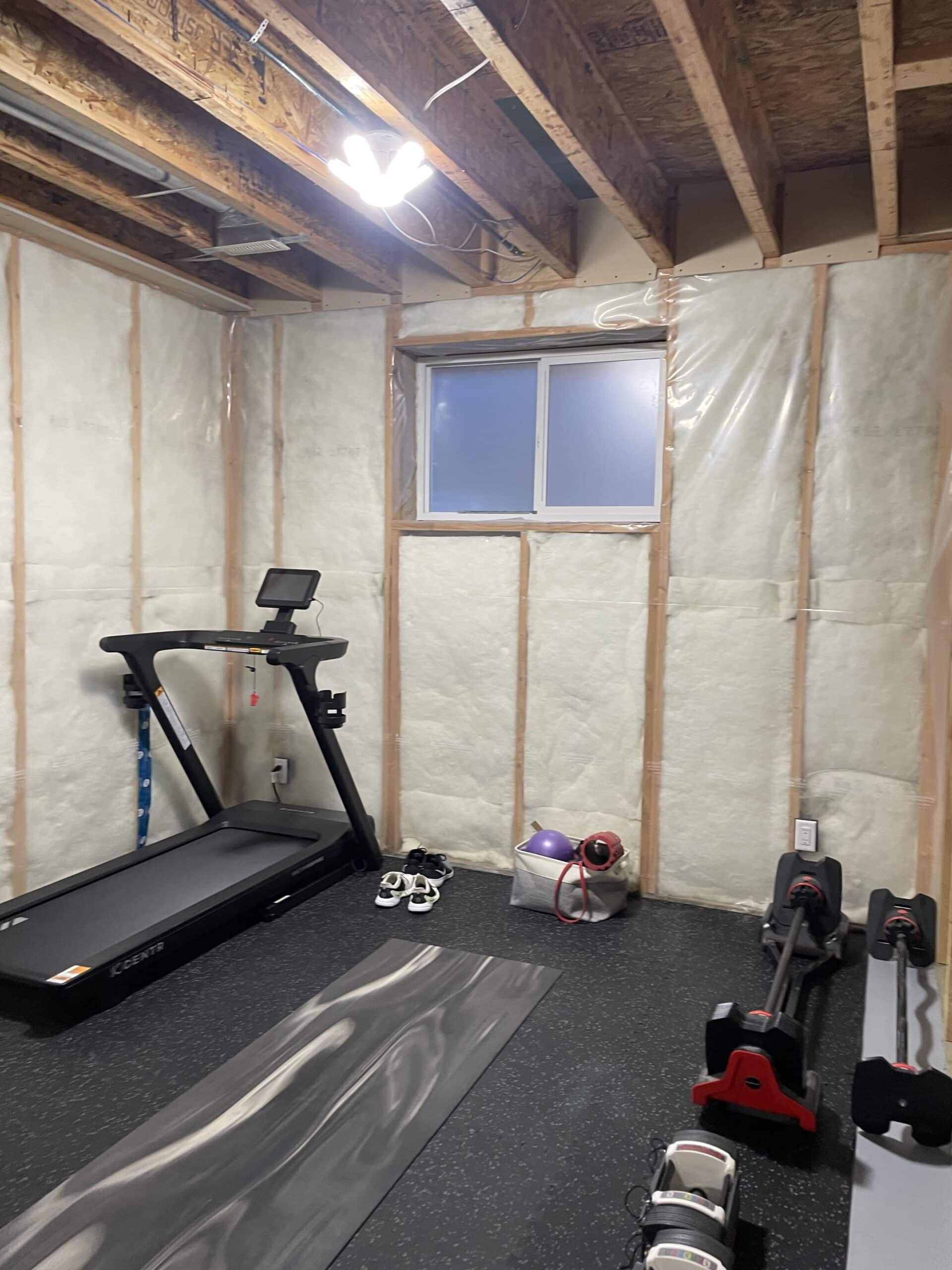 Unfinished Garrison Green Calgary basement before development with exposed framing and insulation in future gym area