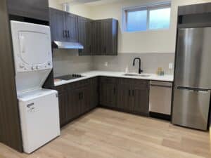 Finished legal basement suite kitchen in Calgary with cabinetry, appliances, sink, dishwasher and laundry
